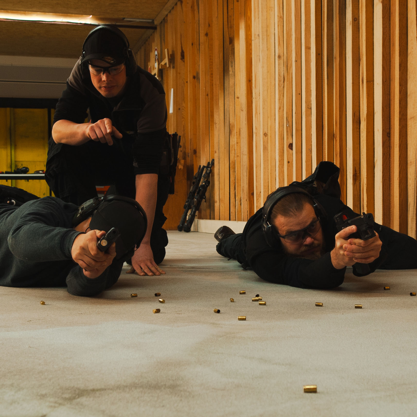 Schießtrainer erklärt dei Haltung der Waffe, wenn man aus einer liegenden Position mit der Pistole schießt